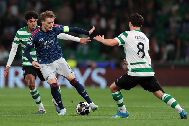 Arsenal's Norwegian midfielder #08 Martin Odegaard (C) fights for the ball with Sporting Lisbon's Portuguese forward #08 Pedro Goncalves and Portuguese defender #72 Eduardo Quaresma (L) during the UEFA Champions League quarter final first leg football match between Sporting CP and Arsenal at Jose Alvalade stadium in Lisbon on April 7, 2026. (Photo by PATRICIA DE MELO MOREIRA / AFP)