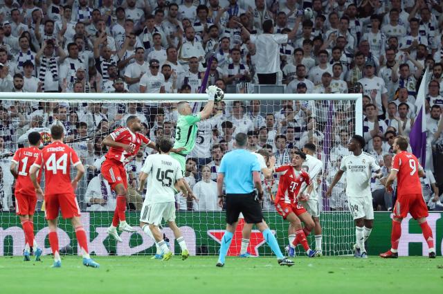 Real Madrid's Ukrainian goalkeeper #13 Andriy Lunin jumps to make a save during the UEFA Champions League quarter final first leg football match between Real Madrid CF and FC Bayern Munich at Santiago Bernabeu Stadium in Madrid on April 7, 2026. (Photo by Pierre-Philippe MARCOU / AFP)