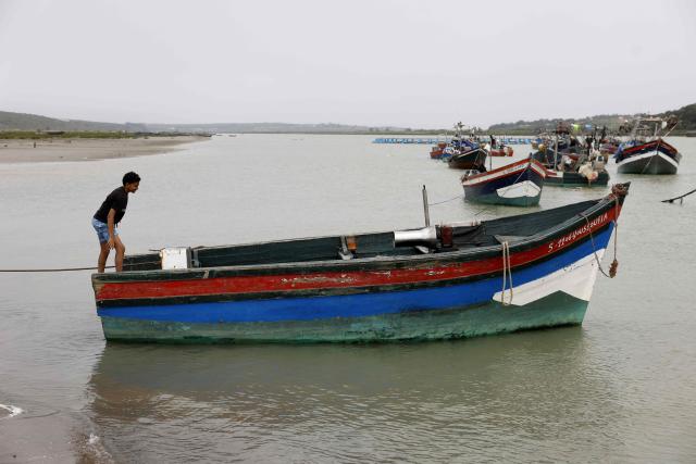 A youth from Chelihat, part of a traditional artisanal fishing community, climbs into a boat moored offshore in Chelihat, Kenitra region on April 7, 2026. (Photo by Abdel Majid BZIOUAT / AFP)