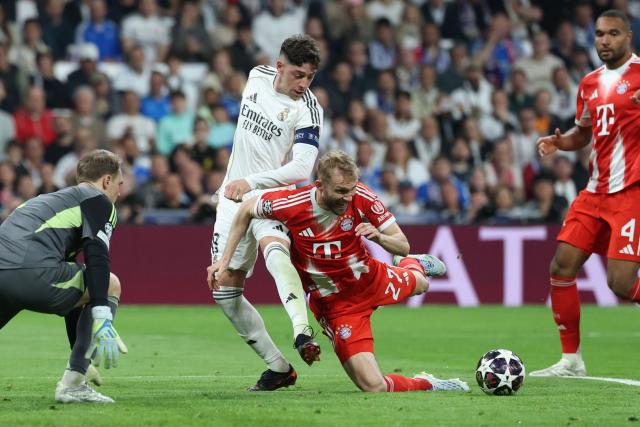 Real Madrid's Uruguayan midfielder #08 Federico Valverde (C) is challenged by Bayern Munich's Austrian midfielder #27 Konrad Laimer during the UEFA Champions League quarter final first leg football match between Real Madrid CF and FC Bayern Munich at Santiago Bernabeu Stadium in Madrid on April 7, 2026. (Photo by Thomas COEX / AFP)