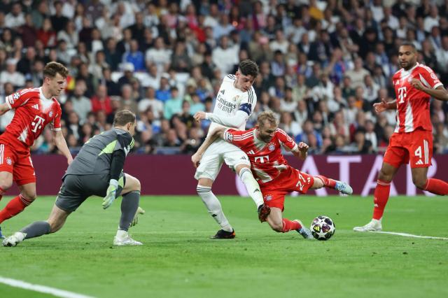 Real Madrid's Uruguayan midfielder #08 Federico Valverde (C) is challenged by Bayern Munich's Austrian midfielder #27 Konrad Laimer during the UEFA Champions League quarter final first leg football match between Real Madrid CF and FC Bayern Munich at Santiago Bernabeu Stadium in Madrid on April 7, 2026. (Photo by Thomas COEX / AFP)