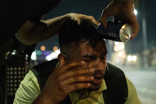 Protesters flush their eyes with liquid after being tear-gassed during a protest outside the Kuwaiti consulate following a strike that killed three people in a nearby town in Basra on April 7, 2026. A strike in Iraq's southern province of Basra on April 7, killed at least three civilians, a provincial councillor and a security official told AFP. A member of Basra's provincial council, said "a house in the city of Khor al-Zubair was struck by what eyewitnesses said was a jet", adding that "neighbours said the house was inhabited by five people, but until now only three bodies have been retrieved". (Photo by Hussein FALEH / AFP)