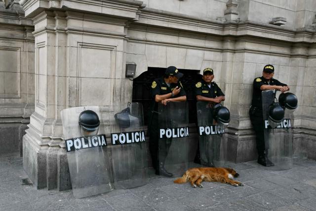 A dog sleeps in front of Peruvian police officers standing guard at the Presidential Palace in Lima on April 7, 2026. Peru will hold presidential elections on April 12, 2026. (Photo by Luis ROBAYO / AFP)