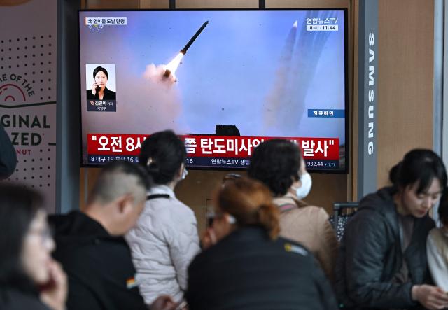 People watch a television screen showing a news broadcast with file footage of a North Korean missile test, at a train station in Seoul on April 8, 2026. North Korea fired multiple short-range ballistic missiles on April 8, South Korea's military said, hours after reporting an "unidentified projectile" launched from the North's capital area the previous day. (Photo by Jung Yeon-je / AFP)