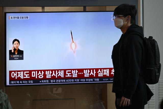 A man walks past a television screen showing a news broadcast with file footage of a North Korean missile test, at a train station in Seoul on April 8, 2026. North Korea fired multiple short-range ballistic missiles on April 8, South Korea's military said, hours after reporting an "unidentified projectile" launched from the North's capital area the previous day. (Photo by Jung Yeon-je / AFP)