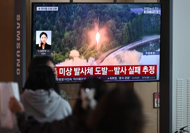 People watch a television screen showing a news broadcast with file footage of a North Korean missile test, at a train station in Seoul on April 8, 2026. North Korea fired multiple short-range ballistic missiles on April 8, South Korea's military said, hours after reporting an "unidentified projectile" launched from the North's capital area the previous day. (Photo by Jung Yeon-je / AFP)