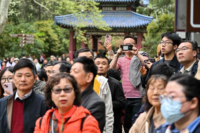 People wait to see the convoy of vehicles transporting Kuomintang Chairperson Cheng Li-wen after she visited the Sun Yat-Sen Mausoleum in Nanjing on April 8, 2026. Taiwan's main opposition leader landed in China on April 7 for a rare visit aimed at building cross-strait "peace", as the Taipei government warned Beijing would seek to stop US arms sales to the democratic island. (Photo by Hector RETAMAL / AFP)