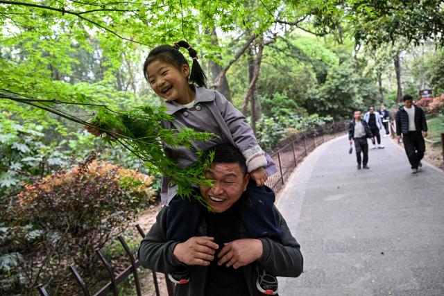 A girl plays with a tree branch at Zhongshan Mountain National Park in Nanjing, in China's eastern Jiangsu province on April 8, 2026. (Photo by Hector RETAMAL / AFP)