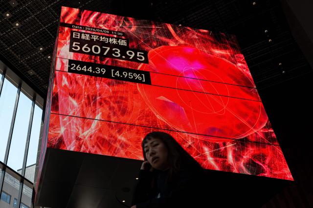 A woman walks past an electronic quotation board displaying the Nikkei 225 stock prices on the Tokyo Stock Exchange in Tokyo on Tokyo on April 8, 2026. (Photo by Philip FONG / AFP)