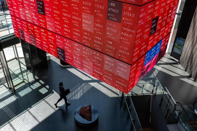 A man walks under an electronic quotation board displaying the Nikkei 225 stock prices on the Tokyo Stock Exchange in Tokyo on Tokyo on April 8, 2026. (Photo by Philip FONG / AFP)