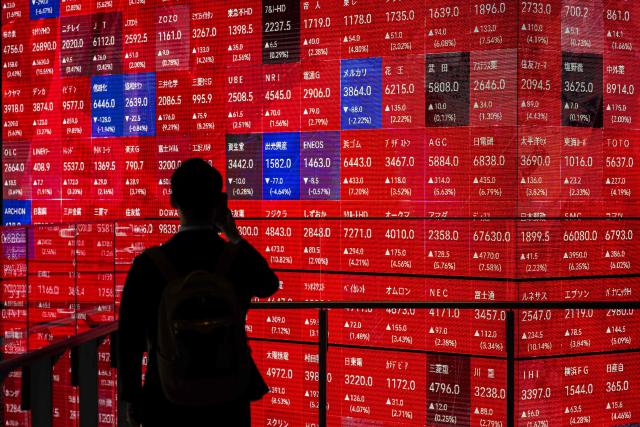 A man takes pictures of an electronic quotation board displaying the Nikkei 225 stock prices on the Tokyo Stock Exchange in Tokyo on Tokyo on April 8, 2026. (Photo by Philip FONG / AFP)