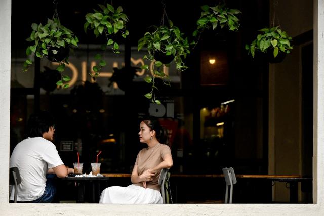 People sit at a cafe's terrace in Hanoi on April 8, 2026. (Photo by Nhac NGUYEN / AFP)
