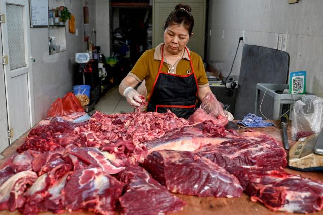 A woman prepares beef for sale at her shop in Hanoi on April 8, 2026. (Photo by Nhac NGUYEN / AFP)