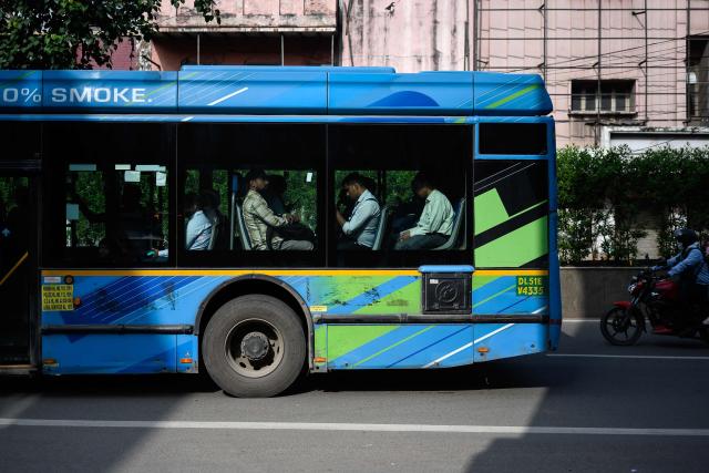 Commuters travel on an electric bus along a road in the old quarters of Delhi on April 8, 2026. (Photo by MANAN VATSYAYANA / AFP)
