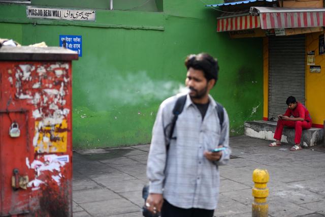 A man checks his smartphone along a street in the old quarters of Delhi on April 8, 2026. (Photo by MANAN VATSYAYANA / AFP)