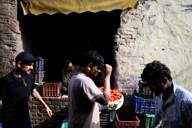 A vegatable vendor (2L) waits for customers at a wholesale market in the old quarters of Delhi on April 8, 2026. (Photo by MANAN VATSYAYANA / AFP)