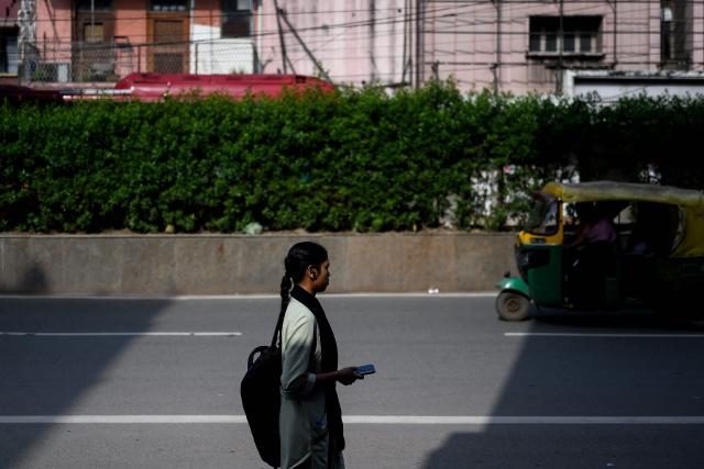 A woman walks along a street in the old quarters of Delhi on April 8, 2026. (Photo by MANAN VATSYAYANA / AFP)