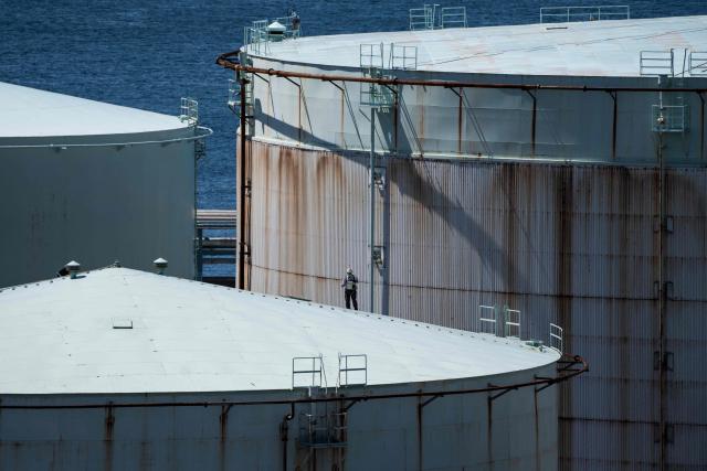 A worker is seen on an oil storage tank at an oil refinery in Yokohama, Kanagawa prefecture on April 8, 2026. (Photo by Yuichi YAMAZAKI / AFP)