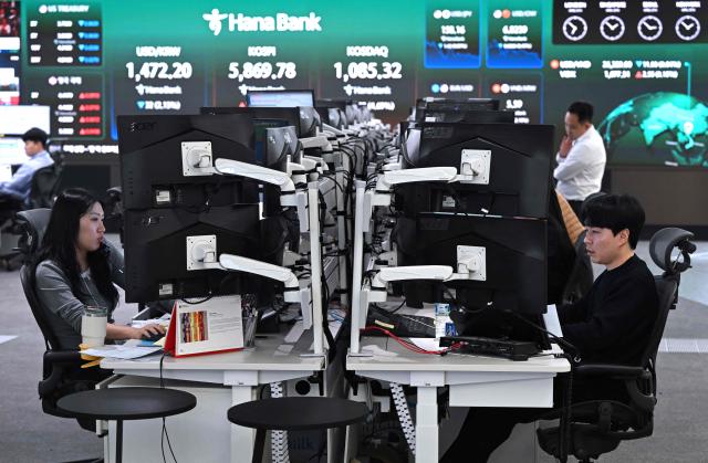 Currency dealers monitor exchange rates as a screen shows South Korea's benchmark stock index (KOSPI) in a foreign exchange dealing room at the Hana Bank headquarters in Seoul on April 8, 2026. (Photo by Jung Yeon-je / AFP)