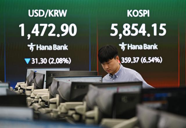 A currency dealer monitors exchange rates as a screen shows South Korea's benchmark stock index (KOSPI) and the Korean won/USD exchange rate in a foreign exchange dealing room at the Hana Bank headquarters in Seoul on April 8, 2026. (Photo by Jung Yeon-je / AFP)