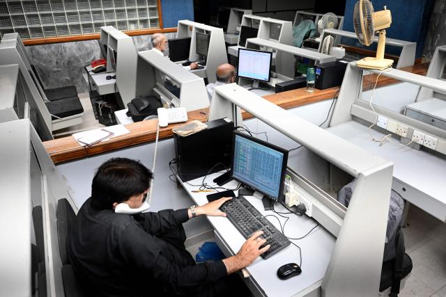 Stockbrokers monitor share prices during a trading session at the Pakistan Stock Exchange (PSX) in Karachi on April 8, 2026. (Photo by Rizwan TABASSUM / AFP)