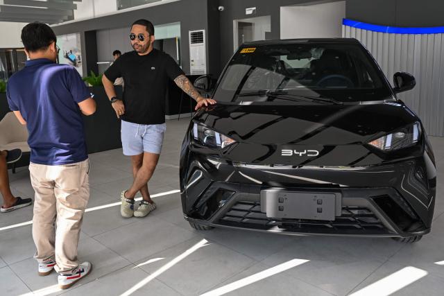 A man talks to a salesman beside a BYD electric car at a dealership in Dasmarinas, province of Cavite on April 8, 2026. (Photo by Jam STA ROSA / AFP)