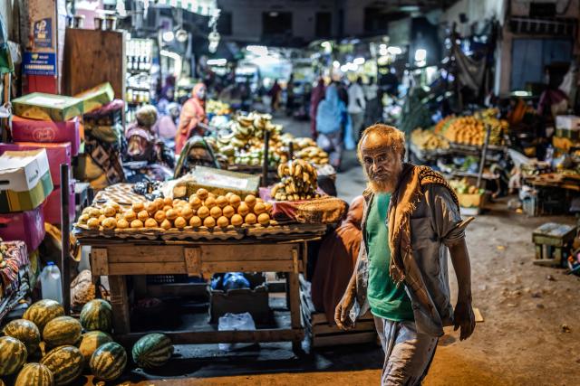 A worker moves through an open-air market as residents take the streets during the cooler evening hours to escape the daytime heat in downtown Djibouti, on April 7, 2026, ahead of the 2026 Djiboutian presidential elections. (Photo by Luis TATO / AFP)