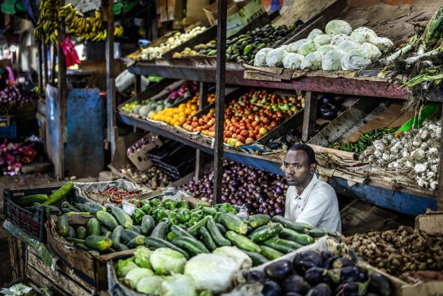 A vegetable seller waits for customers at his stall in an open-air market as residents take the streets during the cooler evening hours to escape the daytime heat in downtown Djibouti, on April 7, 2026, ahead of the 2026 Djiboutian presidential elections. (Photo by Luis TATO / AFP)