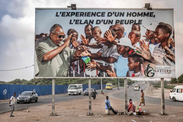 TOPSHOT - Residents gather beneath an electoral banner in support of Djibouti’s incumbent president and presidential candidate Ismail Omar Guelleh in Djibouti, on April 8, 2026, ahead of the 2026 Djiboutian presidential elections. (Photo by Luis TATO / AFP)