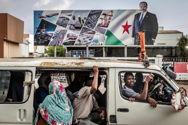 TOPSHOT - Residents board a minibus in front of an electoral banner in support of Djibouti’s incumbent president and presidential candidate Ismail Omar Guelleh in Djibouti, on April 8, 2026, ahead of the 2026 Djiboutian presidential elections. (Photo by Luis TATO / AFP)
