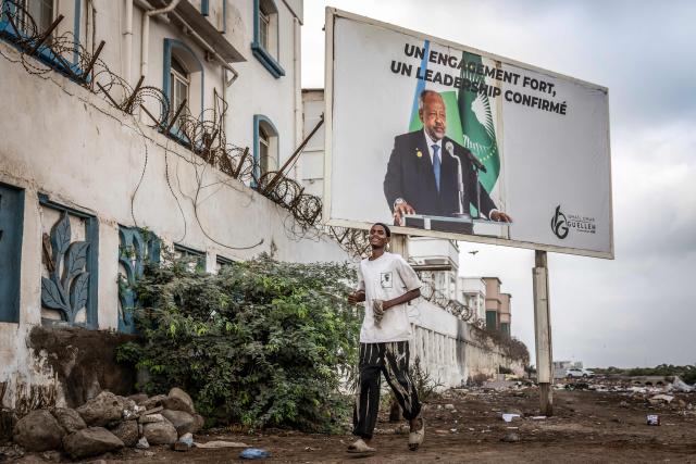 A man walks past an electoral banner in support of Djibouti’s incumbent president and presidential candidate Ismail Omar Guelleh in Djibouti, on April 8, 2026, ahead of the 2026 Djiboutian presidential elections. (Photo by Luis TATO / AFP)