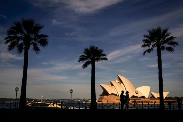 A couple pose for their wedding portraits in front of the Sydney Opera House on an Autumn day in Sydney on April 8, 2026. (Photo by DAVID GRAY / AFP)