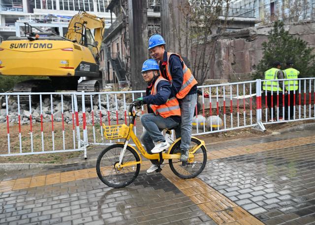 Workers ride a bicycle at a construction site for a futuristic innovation hub project in Shougang area, Shijingshan district in Beijing on April 8, 2026. (Photo by ADEK BERRY / AFP)