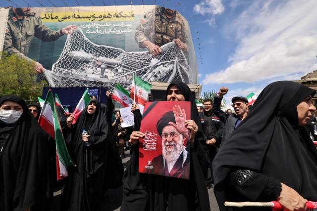 Iranians hold national flags and portraits of the country’s slain supreme leader Ayatollah Ali Khamenei as they gather in Tehran's Revolution Square after the United States and Iran agreed to a two-week ceasefire, on April 8, 2026. The United States and Iran agreed to a two-week ceasefire barely an hour before the US president's April 8 deadline to obliterate the country, triggering global relief alongside apprehension. (Photo by ATTA KENARE / AFP) / 