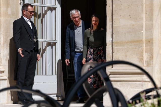 French nationals Jacques Paris (L) and Cecile Kohler (R) who were freed by Iran after three and a half years in detention walk as they are hosted by French President at the Elysee Palace in Paris, on April 8, 2026. The pair had been under house arrest at the French embassy in Tehran ever since being freed from more than three years in prison in November, with their fate even more uncertain after US-Israeli strikes on Iran started on February 28. (Photo by Tom Nicholson / POOL / AFP)