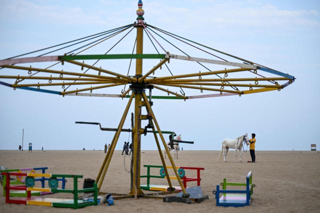 A horseman who makes a living by giving beachgoers horse rides waits for customers at Marina Beach in Chennai on April 8, 2026. (Photo by R. Satish BABU / AFP)