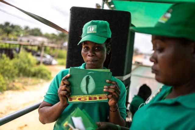 A supporter holds a banner of the Force Cauris pour un Benin Emergent (FCBE) party in an election caravan on the road to Ouidah, on April 08, 2026. (Photo by OLYMPIA DE MAISMONT / AFP)