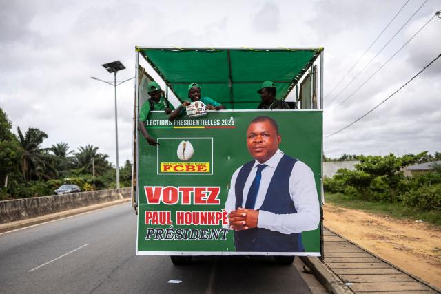 Supporters hold banners in an election caravane bearing a billboard of Paul Hounkpe, presidential candidate of the Force Cauris pour un Benin Emergent (FCBE) party on the road to Ouidah, on April 8, 2026. (Photo by OLYMPIA DE MAISMONT / AFP)