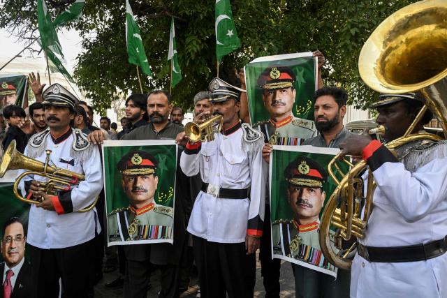 Awami Rickshaw Union workers hold posters of Pakistan's Chief of Army Staff Field Marshal Asim Munir, celebrate after the United States and Iran agreed to a two-week ceasefire, in Lahore on April 8, 2026. Pakistan's Prime Minister Shehbaz Sharif said on April 8 that Islamabad would host delegations from the United States and Iran later this week following their ceasefire announcement. (Photo by Arif ALI / AFP)