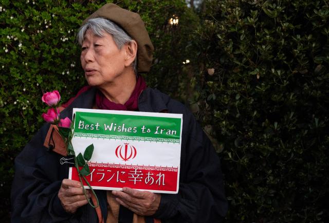 A protester holds up an anti-war poster during a demonstration by opposition political groups and activists across the street from the Diet, Japan’s House of Representatives, in central Tokyo, on April 8, 2026 to oppose revisions to the Constitution and protest attacks by the United States and Israel on Iran. (Photo by Andrew CABALLERO-REYNOLDS / AFP)
