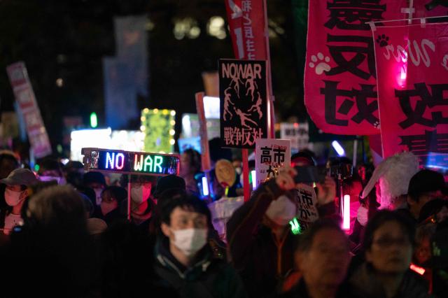 Protesters hold up placards during a demonstration by opposition political groups and activists across the street from the Diet, Japan’s House of Representatives, in central Tokyo on April 8, 2026 to oppose revisions to the Constitution and protest attacks by the United States and Israel on Iran. (Photo by Andrew CABALLERO-REYNOLDS / AFP)