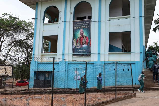 Schoolchildren from La Retraite College walk past a building displaying a portrait of Pope Leo XIV, in Yaounde on April 8, 2026. (Photo by Daniel BELOUMOU OLOMO / AFP)