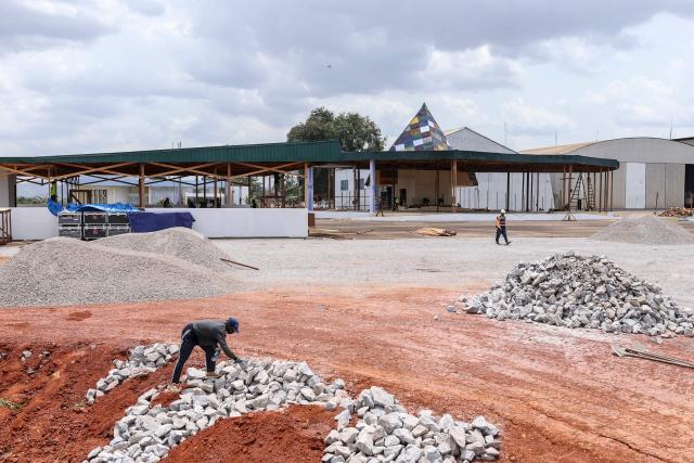 A worker picks up a stone at the wooden church currently under construction at 101 Air Base, where Pope Leo XIV’s final Mass during his visit will be celebrated, in Yaounde on April 8, 2026. (Photo by Daniel BELOUMOU OLOMO / AFP)