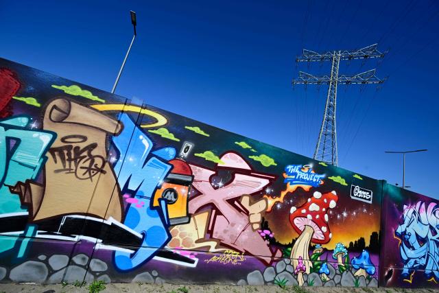 Mural art produced by artists Akte One and Cren appear in the recently unveiled "Sued Ost Galerie" open air collaborative graffiti art exhibition in Berlin on April 8, 2026. The 450-metre-long noise protection wall located in the capital's south east features mural art by some 20 artists collaborating around German rapper and street artist Akte One (Mark Marquardt) who initiated the project in 2025. (Photo by John MACDOUGALL / AFP)