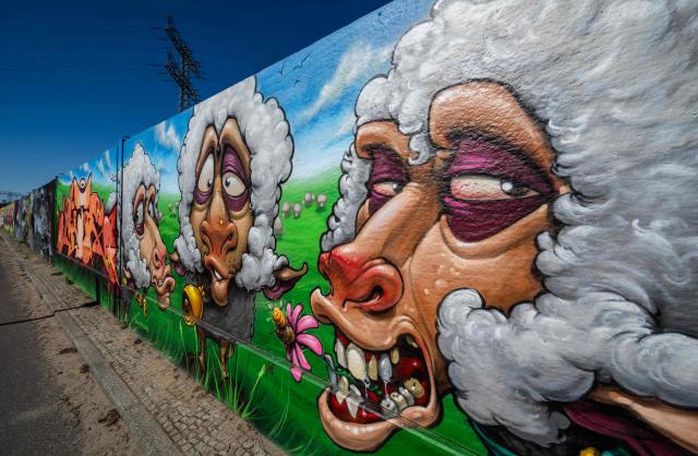 Mural art produced by artist Gino Fuchs appears in the recently unveiled "Sued Ost Galerie" open air collaborative graffiti art exhibition in Berlin on April 8, 2026. The 450-metre-long noise protection wall located in the capital's south east features mural art by some 20 artists collaborating around German rapper and street artist Akte One (Mark Marquardt) who initiated the project in 2025. (Photo by John MACDOUGALL / AFP)