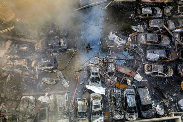 A firefighter walks past destroyed vehicles as colleagues attempt to extinguish a fire following an Israeli strike at the Corniche al-Mazraa neighbourhood of Beirut on April 8, 2026. Around 2:00 pm (1100 GMT), a series of Israeli strikes slammed into the Lebanese capital without warning, triggering scenes of panic. Israeli strikes on Lebanon on April 8, the heaviest since the war began in early March, left "dozens dead and hundreds wounded," according to a preliminary toll from the health ministry. (Photo by ibrahim AMRO / AFP)