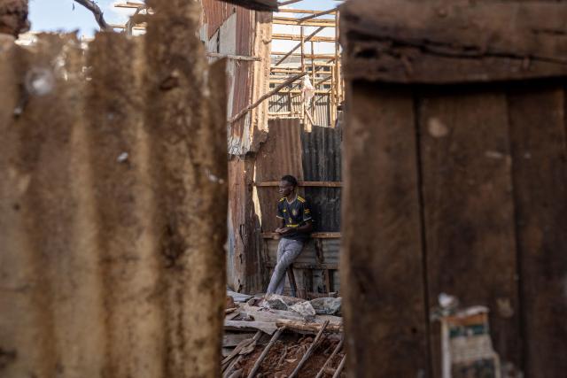 A resident leans on a partly demolished house next to the scene of the collapsed building that killed three people and injuring several others, at the Nyayo high-rise, Soweto village in Kibera, Nairobi on April 8, 2026. (Photo by SIMON MAINA / AFP)