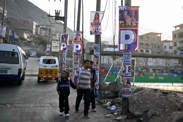 A man and his children walk past in the Villa Maria del Triunfo neighborhood in Lima, on April 8, 2026. Peruvians will choose from a bewildering array of 35 presidential candidates on April 12, 2026, electing the next leader of an Andean nation beset by crime and a string of short-lived, scandal tainted presidencies. (Photo by Luis ROBAYO / AFP)