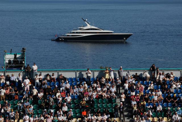 Audience members attend the Monte Carlo ATP Masters Series Tournament at the Monte-Carlo Country Club as a 79.9-metre Feadship superyacht 'Faith' owned by Canadian businessman Lawrence Stroll, majority shareholder of British luxury carmaker Aston Martin is seen in the background, off the coast of Roquebrune-Cap-Martin, south-eastern on April 8, 2026. (Photo by Valery HACHE / AFP)