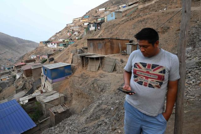 A man looks at his mobile phone in the Villa Maria del Triunfo neighborhood in Lima, on April 8, 2026. Peruvians will choose from a bewildering array of 35 presidential candidates on April 12, 2026, electing the next leader of an Andean nation beset by crime and a string of short-lived, scandal tainted presidencies. (Photo by Luis ROBAYO / AFP)